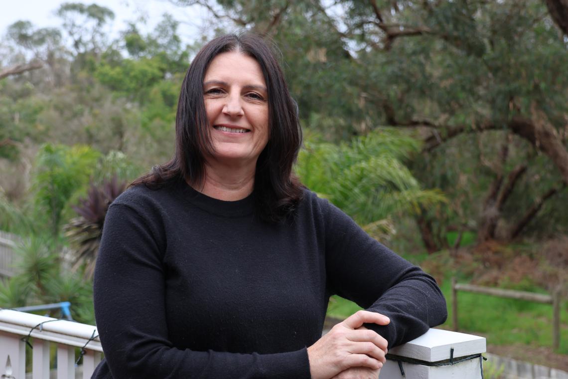 Kris Clements - a Community Worker standing outside on a balcony.